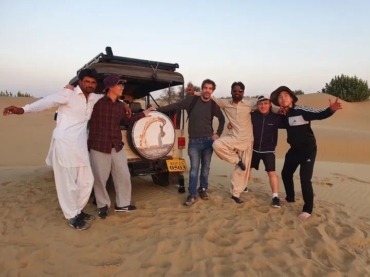 Wonbin guides and guests standing together beside the safari jeep at dusk