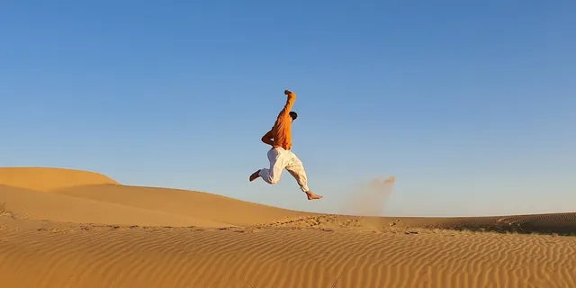 An empty dune in the Thar Desert, with one of the team mid-leap against an open sky