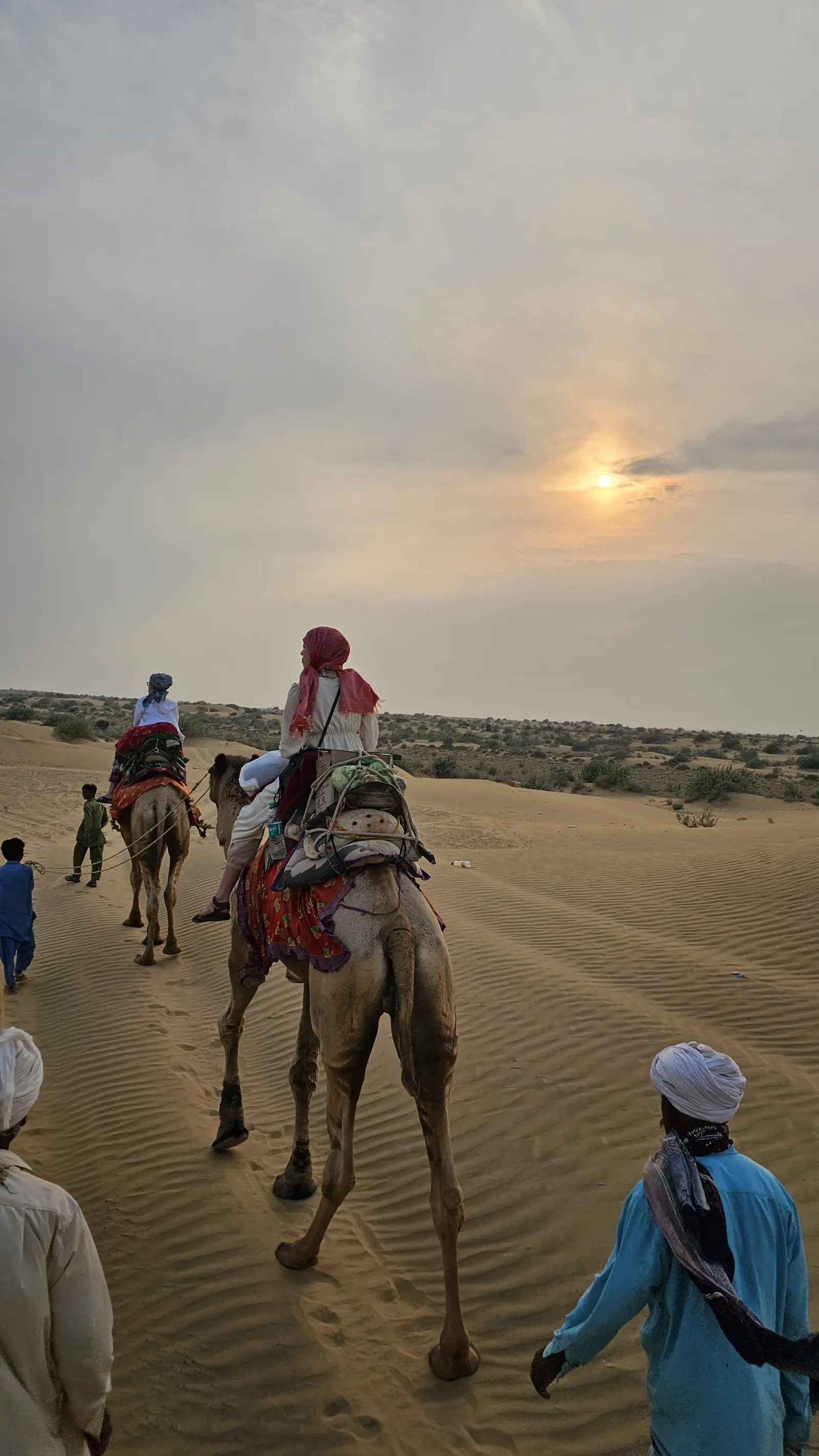 Riders coming over a dune with the cameleers walking alongside