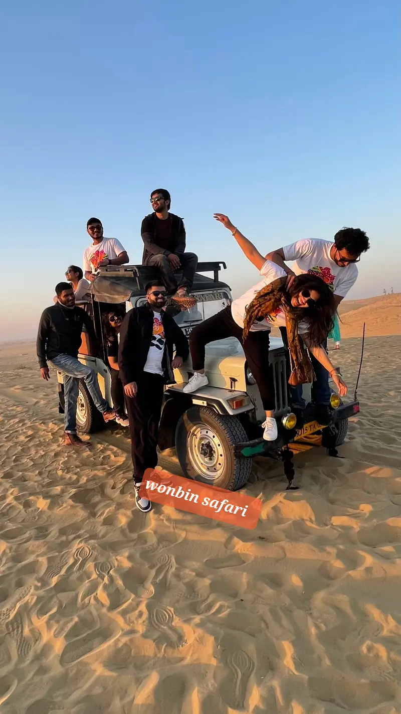 A group climbing onto the jeep out on the sand