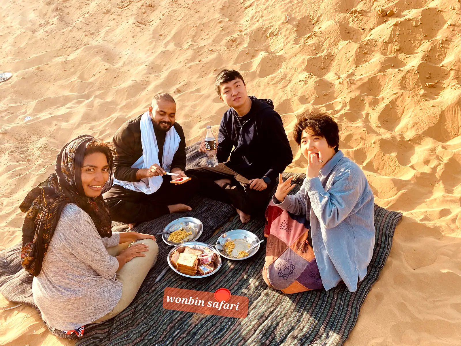 Guests sharing a meal on a blanket spread over the sand