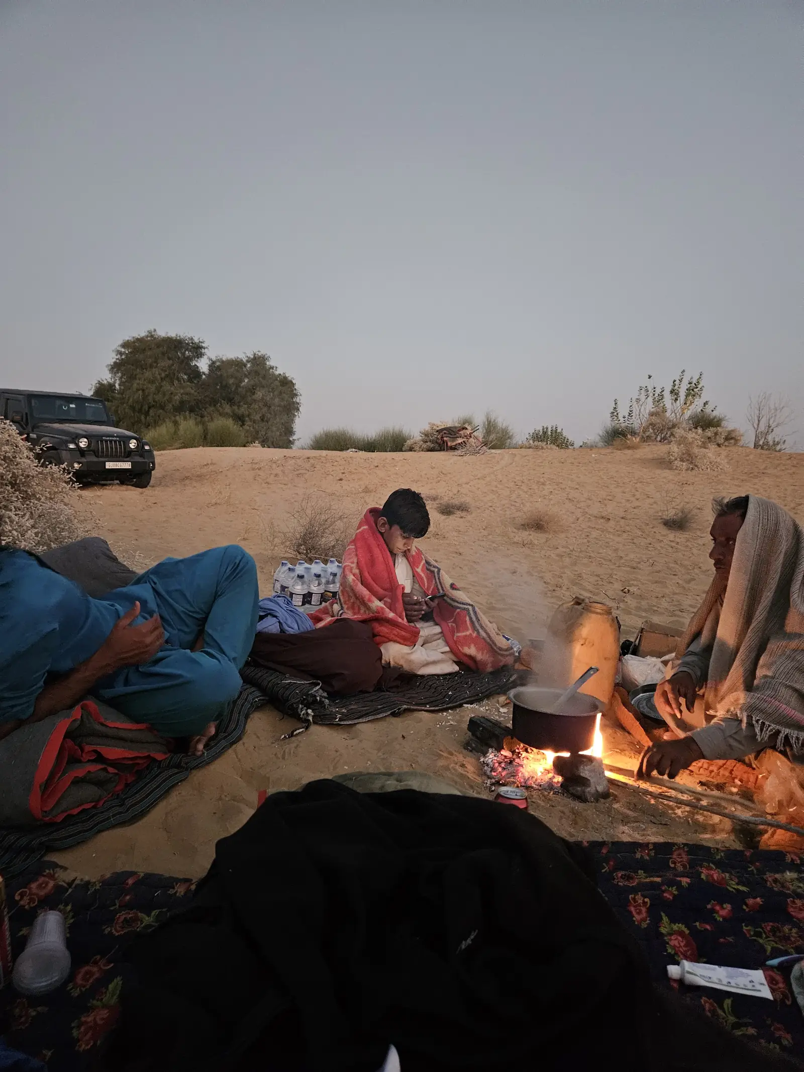 Guests around the fire at dusk with the jeep parked behind