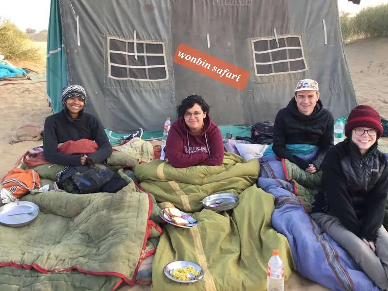 Guests eating together under canvas, wrapped in blankets