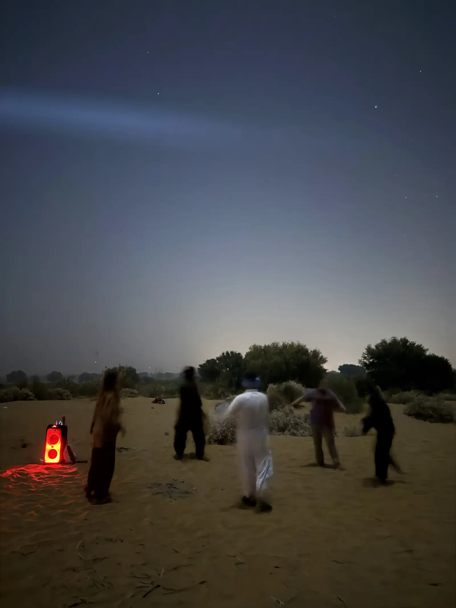 A lantern set down on the sand, guests standing around it