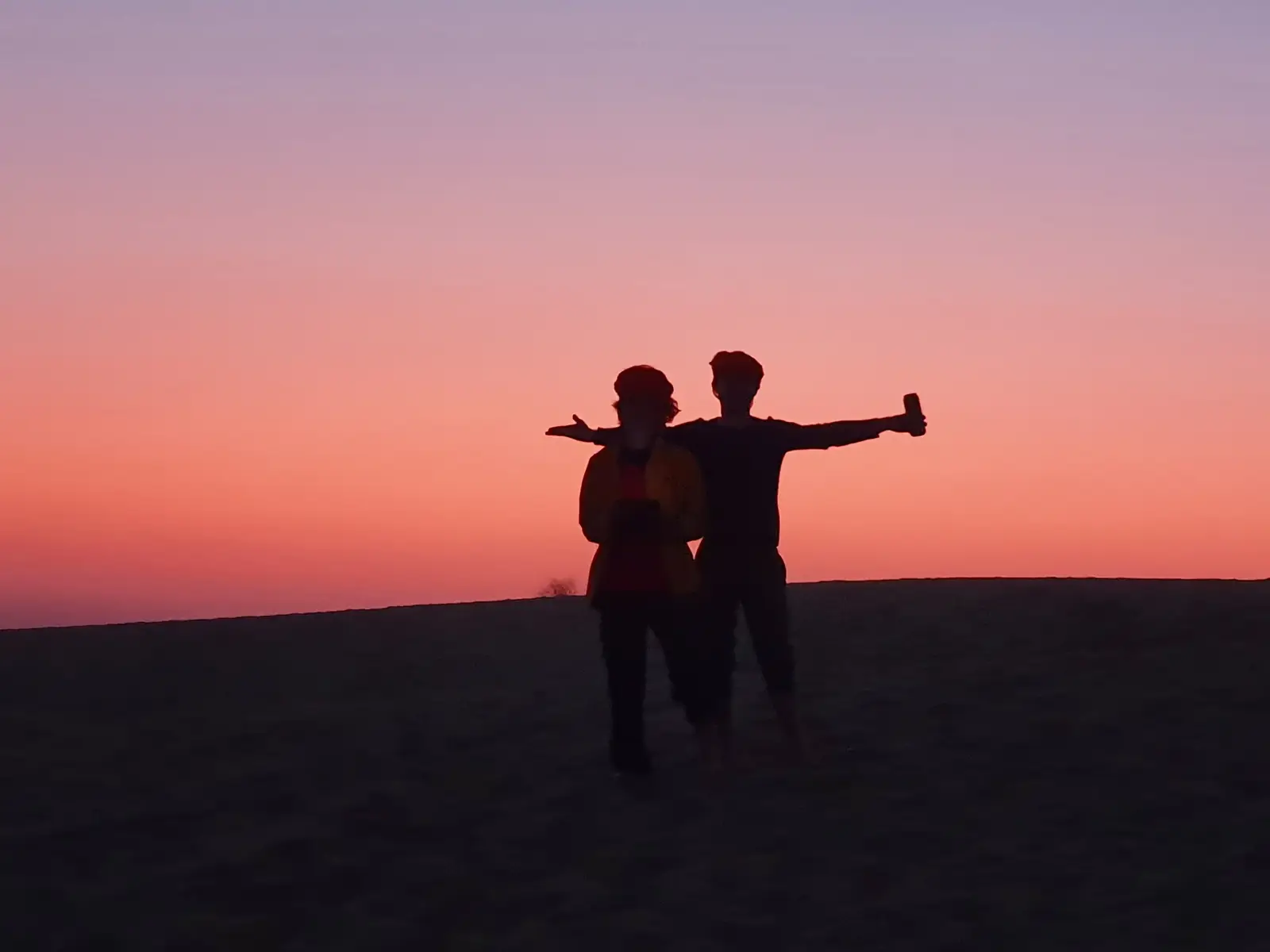 Two guests silhouetted against a pink sky at the end of the day