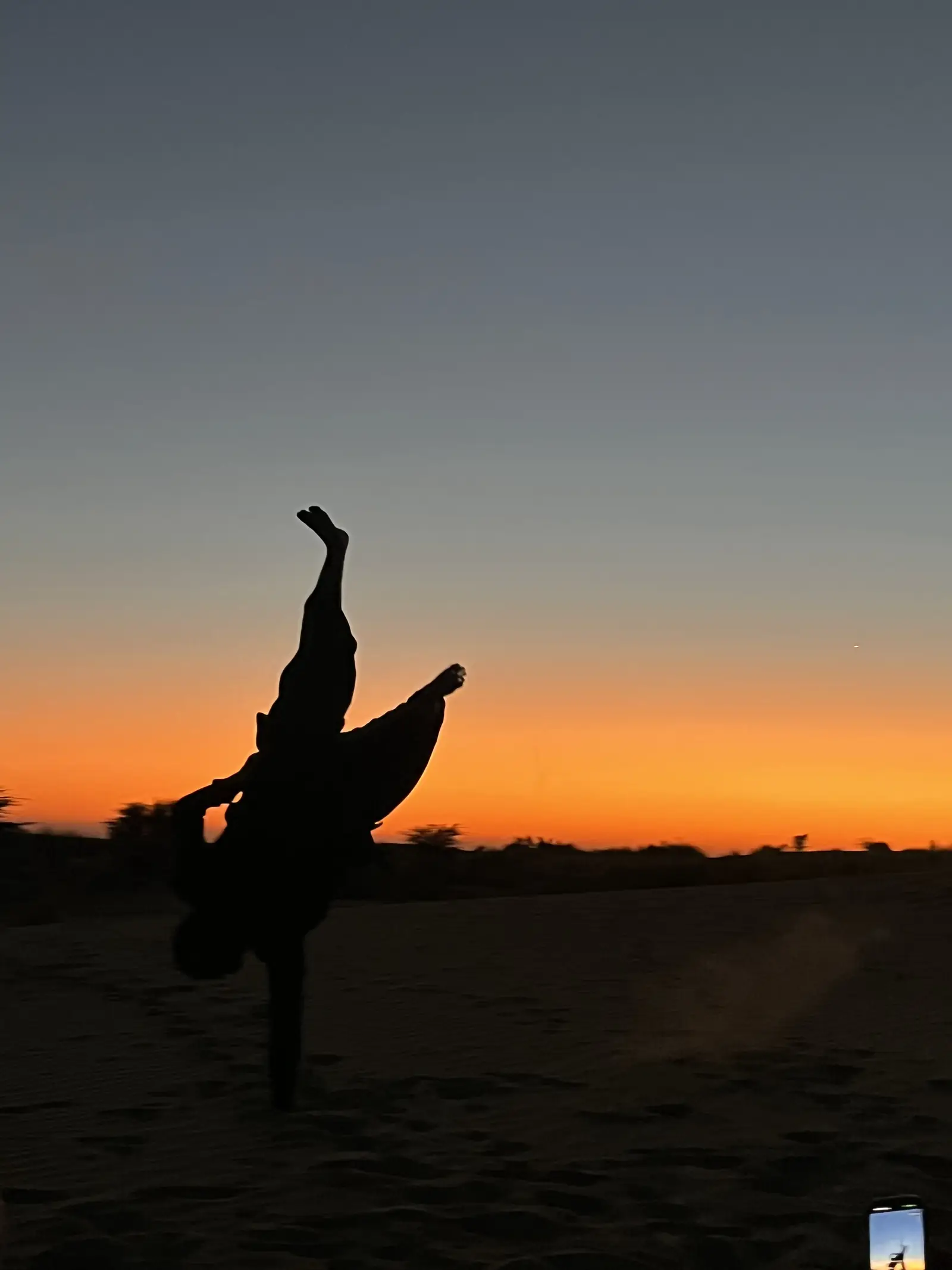 A guest doing a handstand against the last of the light