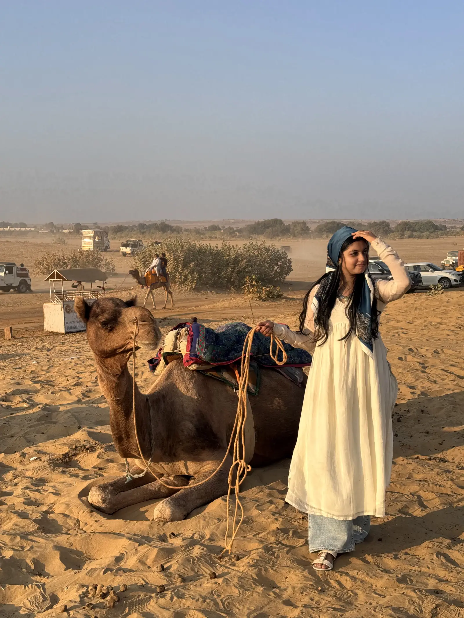 A guest standing with a camel as the light goes orange