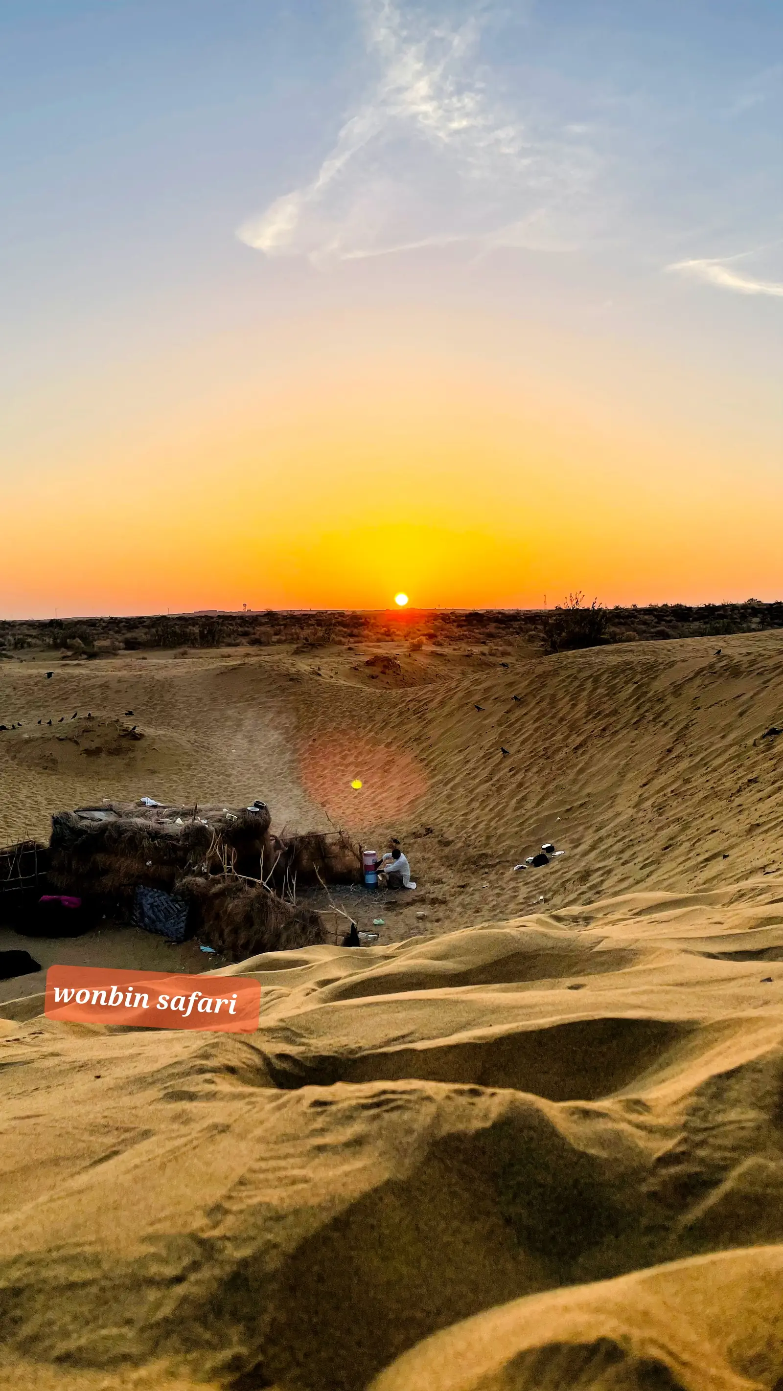 The sun dropping to the horizon over an empty stretch of dunes