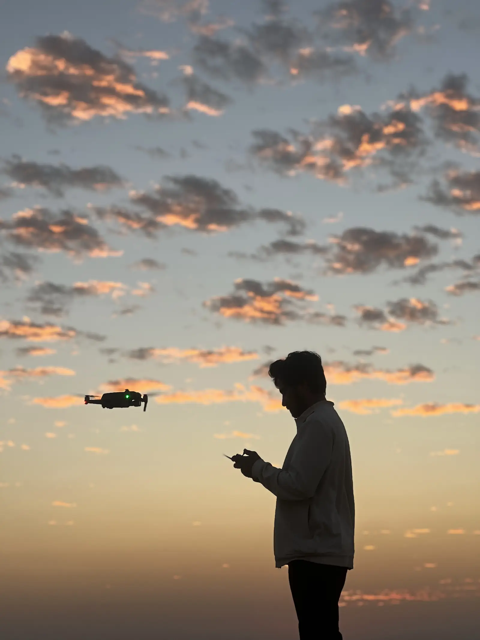 Flying a drone over the dunes as the sun sets behind the cloud