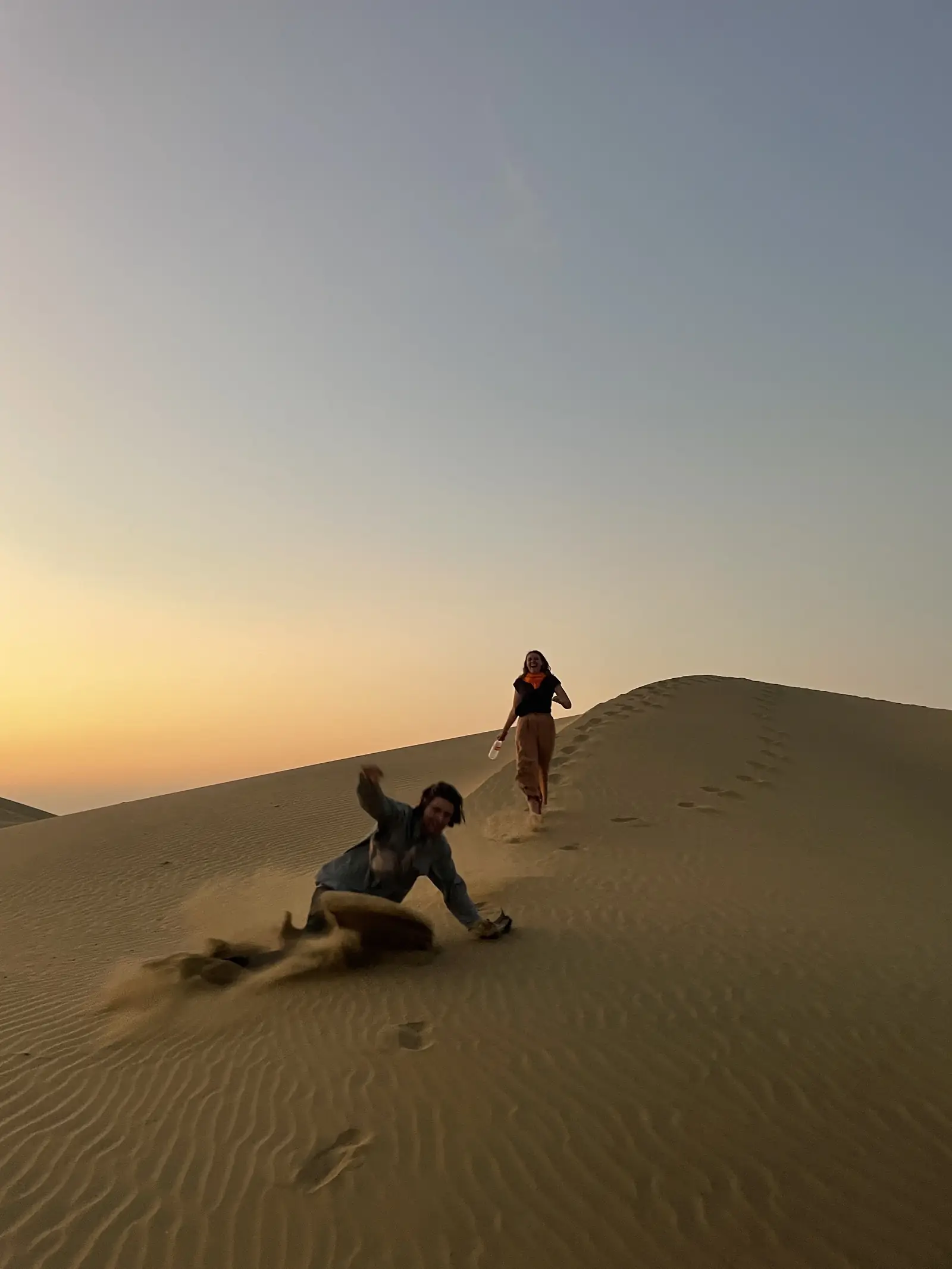 A guest climbing a dune with the sun going down behind
