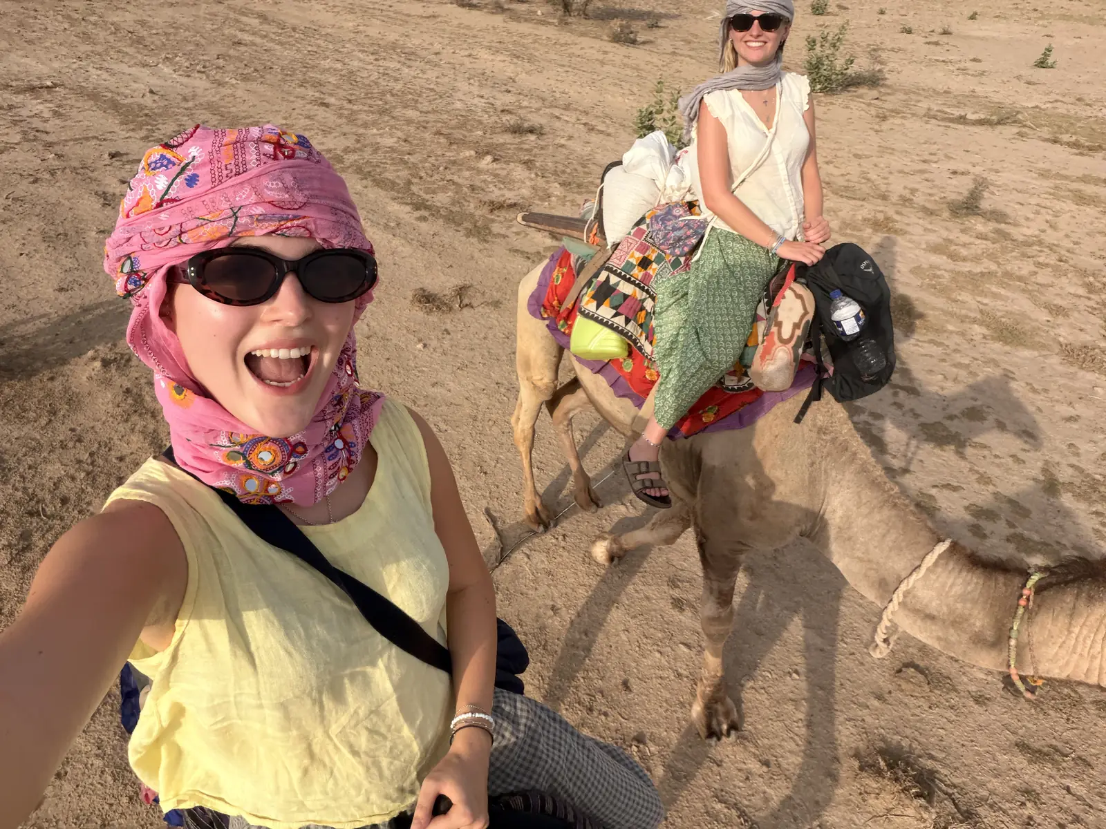 A guest in a pink turban with the saddled camels waiting behind