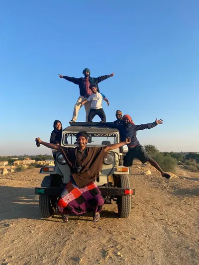 Guests sitting and standing on the roof of the jeep on the track out of town