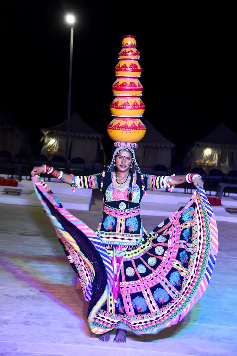 A Kalbeliya dancer in a mirrored skirt performing at the camp after dark