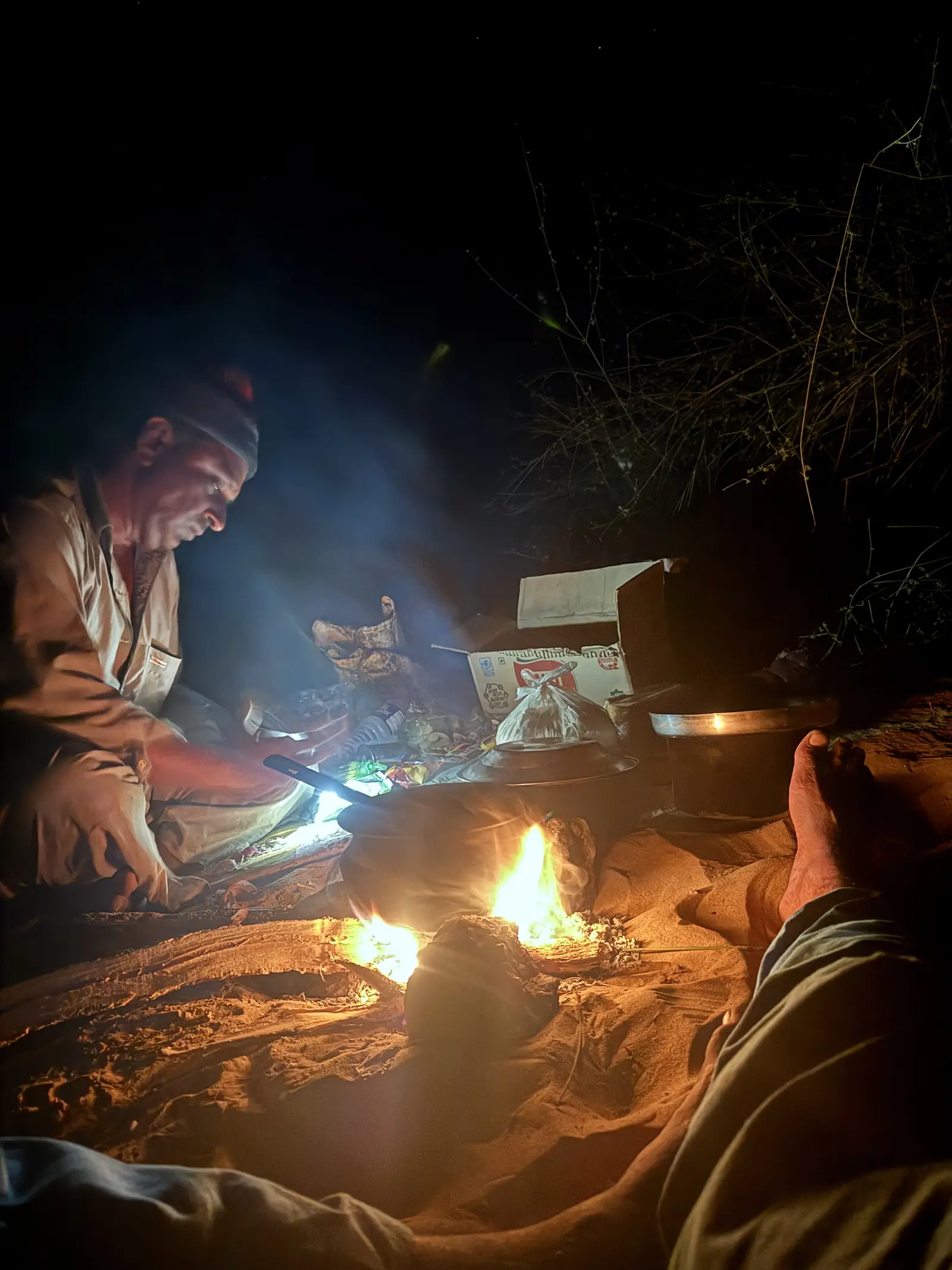 Dinner being cooked over the open fire in the dark at camp