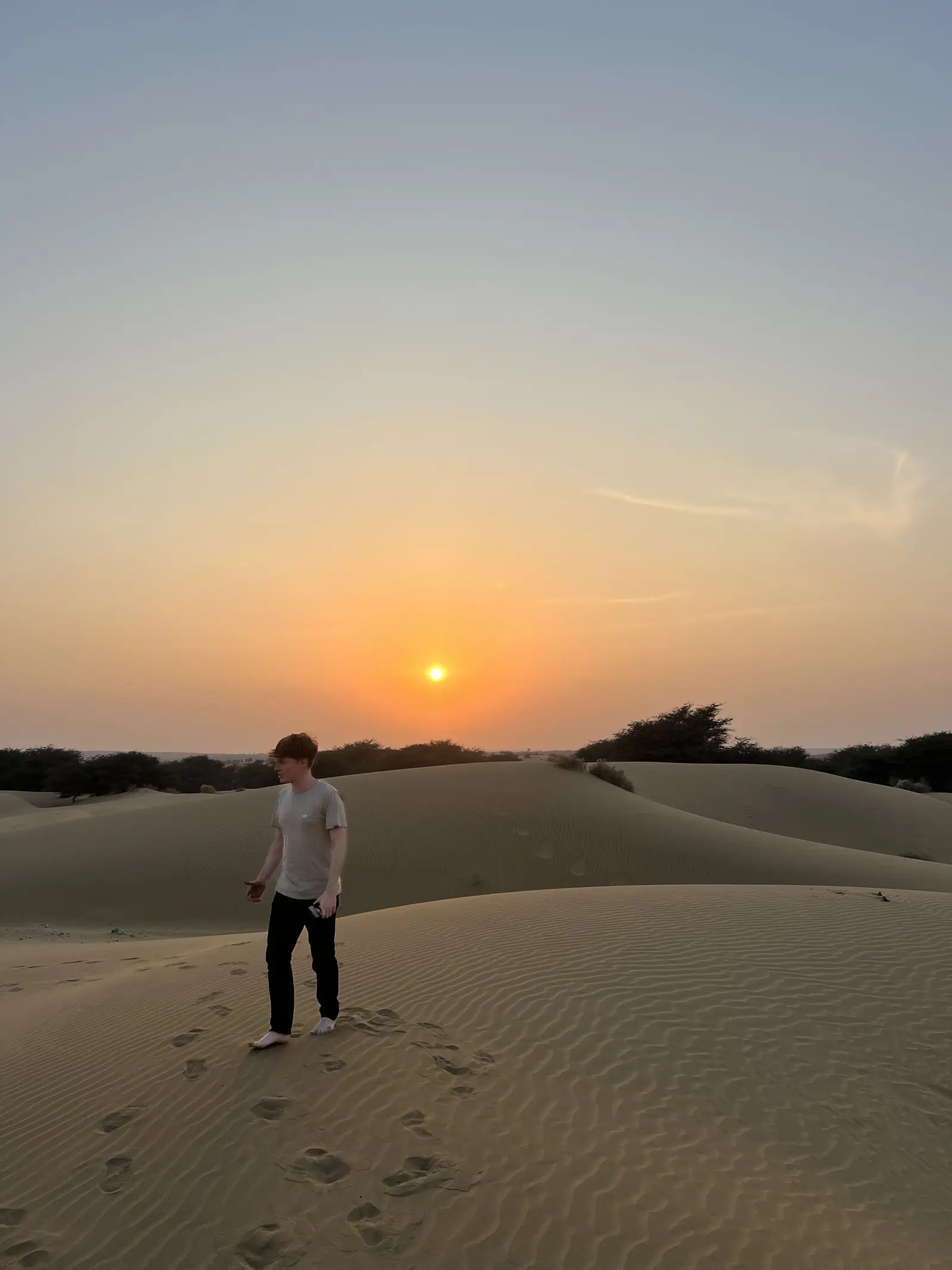 A single figure walking the ridge of a dune in the last of the light