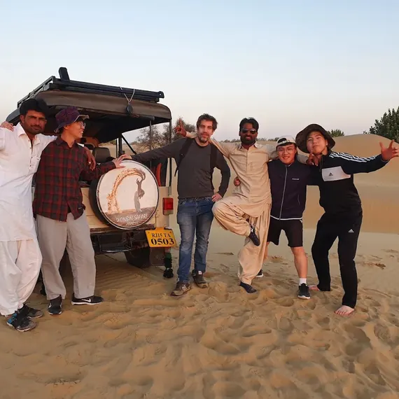 A group beside the Wonbin Safari jeep out on the dunes