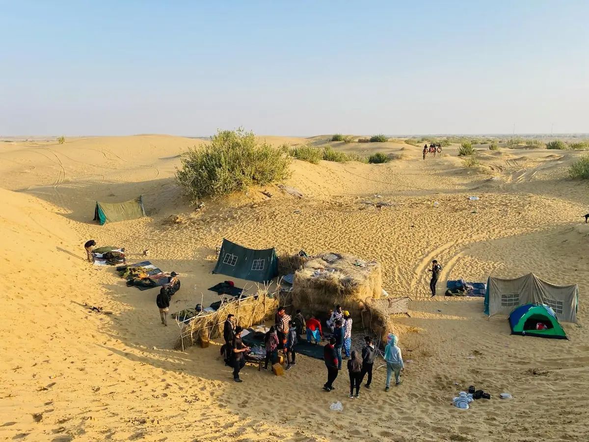 The Wonbin desert camp seen from the dune above, bedding and shelters laid out on the sand