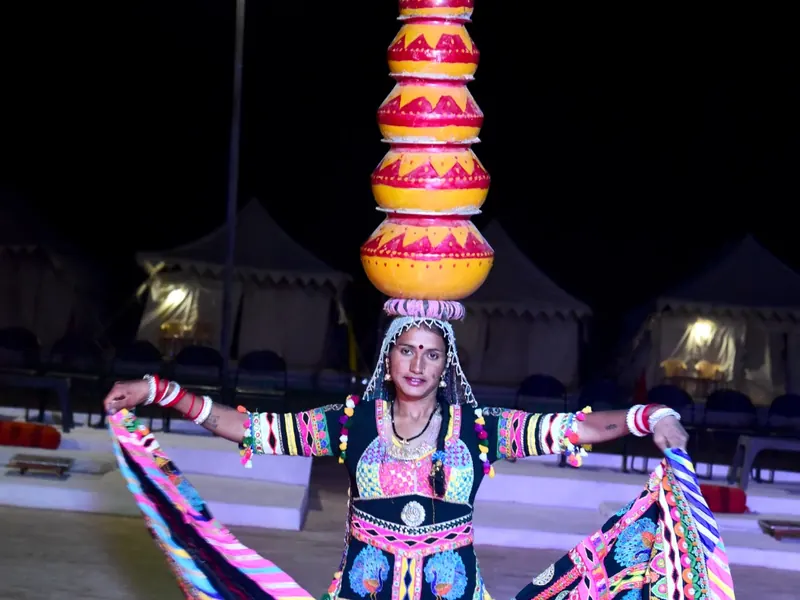A Kalbeliya dancer performing at the camp after dark, pots balanced on her head