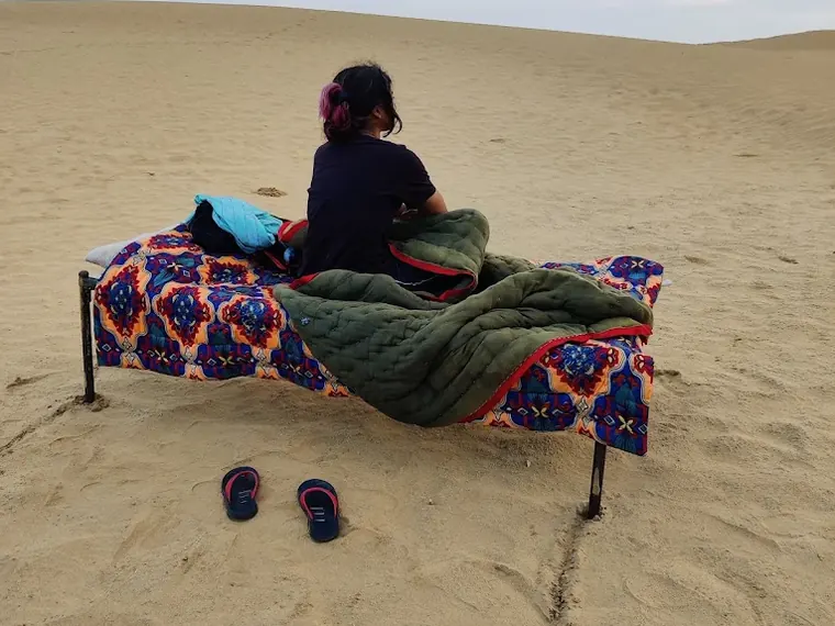 A bed made up on the open sand, with blankets, at the Siala camping ground