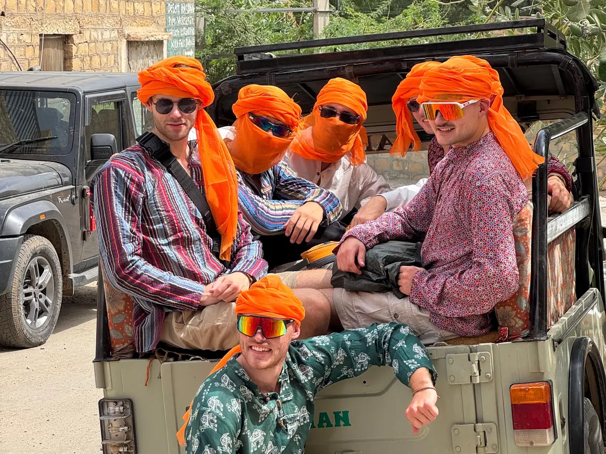 Guests in orange turbans in the back of the safari jeep before the drive out