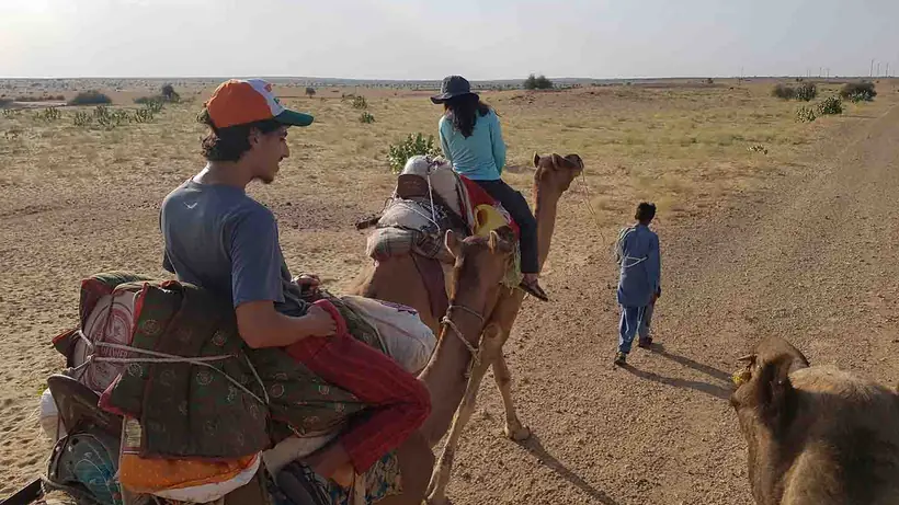 A camel train with guides walking out across the Thar desert