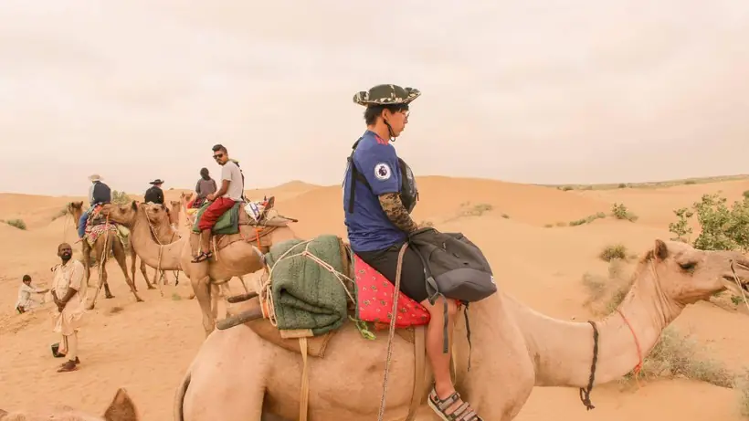 A camel caravan crossing sunlit dunes in the Thar desert near Jaisalmer