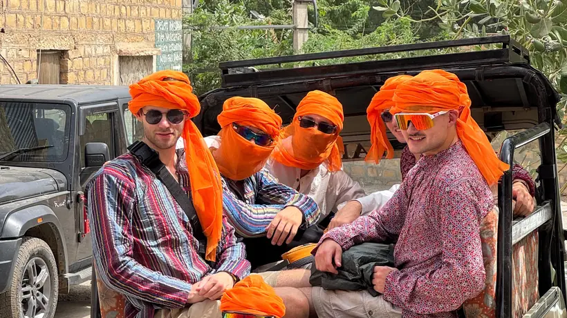 Guests in orange turbans in the back of the safari jeep before an all-day desert trip