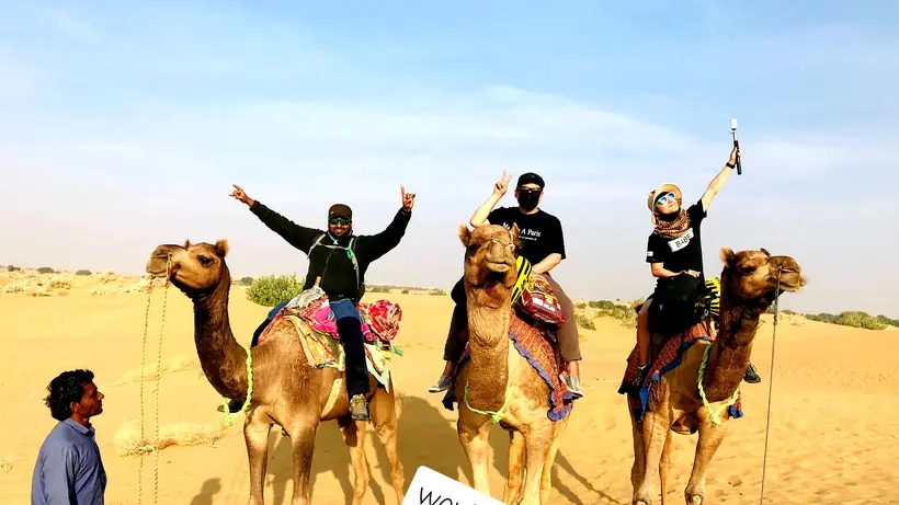 Riders on camels crossing high dunes deep in the Thar desert